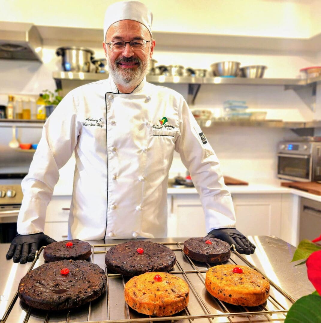 Chef presenting assorted cakes in kitchen.